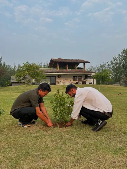 The act of planting a tree is a meditation in itself. Two members of our community carefully place a new sapling in the ground, a simple but powerful act of land restoration.