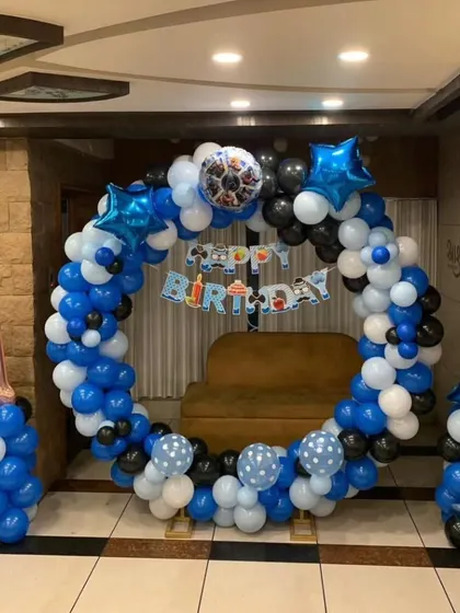 A simple yet elegant circular balloon arch for a first birthday. The blue, black, and white color scheme creates a modern and clean look for a celebration.