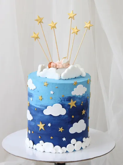 A dreamy "Twinkle Twinkle Little Star" cake to welcome a new baby. The cake has a beautiful blue ombre night sky effect, decorated with fondant clouds, stars, and a sleeping baby on top.