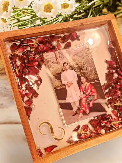 I preserved this couple's varmala in a beautiful wooden tray. The deep red rose petals are scattered around their photo, accented with small pearls, creating a timeless keepsake of their special day.