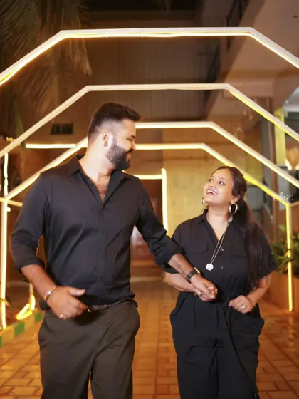 A candid shot of an expecting couple walking through a lit-up corridor. The warm lighting adds to the intimacy of the moment.