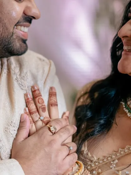 A close-up of the couple's hands and smiling faces after the ring exchange, a perfect symbol of their new commitment.
