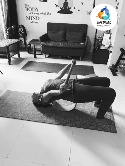 A client uses a yoga wheel and strap to assist with a deep bridge pose variation, allowing for greater opening in the chest and shoulders.