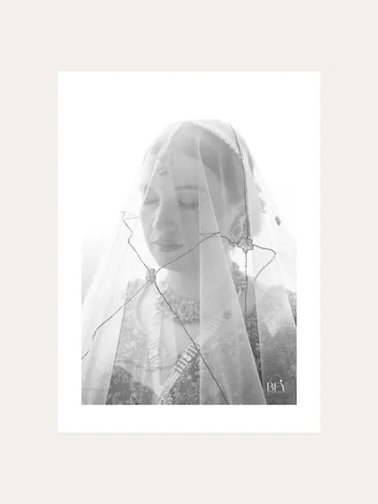 A high-key black and white portrait of a bride under her veil, creating a soft and ethereal look.