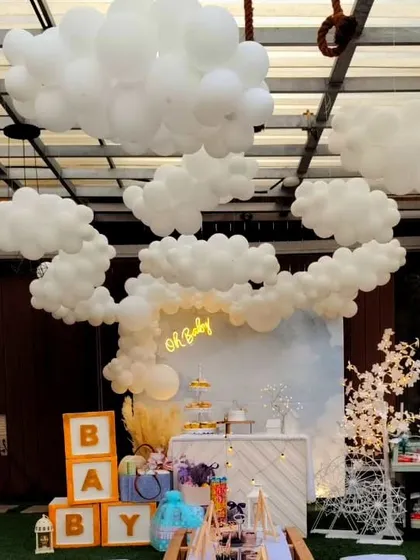 A dreamy "Oh Baby" shower with a celestial, cloud-like atmosphere. I created an installation of white balloons on the ceiling to look like clouds, with a simple backdrop and neon sign below.