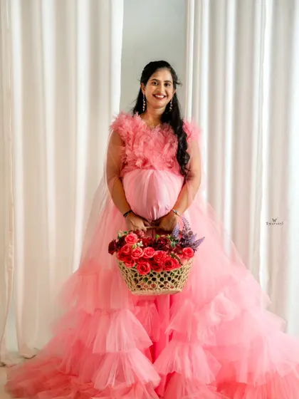 Holding a basket of fresh flowers adds a touch of natural beauty to this maternity portrait. The client looks radiant in the pink ruffled gown.