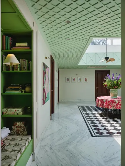 The atrium acts as a central corridor, connecting different parts of the home. Here, you can see the transition from the bold checkered floor to the leafy green reading nook, showcasing the home's playful use of color.