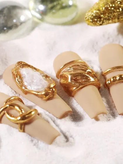 This design showcases how to use gold molding gel to create 3D ring and chain effects on a matte nude base, offering a modern and edgy take on nail jewelry.