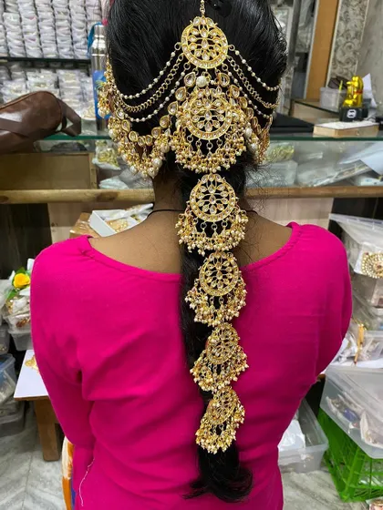 Complete your bridal hairstyle with this stunning gold-plated hair accessory, known as a braid paranda. This intricate piece is available for rent and adds a traditional, royal touch to your wedding look.