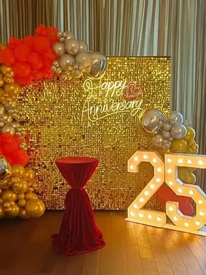 A grand 25th-anniversary celebration with a gold shimmer wall, a balloon arch in red, gold, and silver, and '25' marquee numbers.