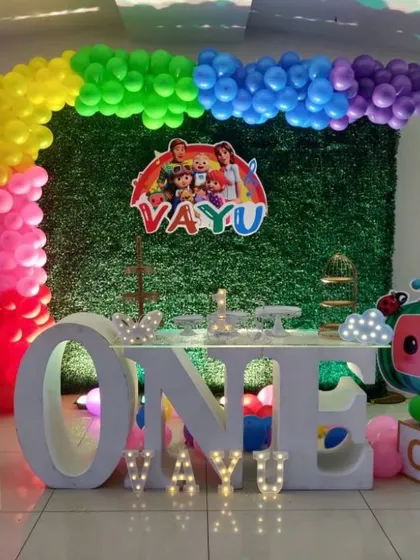 A colorful Cocomelon setup for Vayu's first birthday. We combined a grass wall backdrop with a rainbow balloon arch and a large 'ONE' table prop that's perfect for the cake-cutting ceremony.
