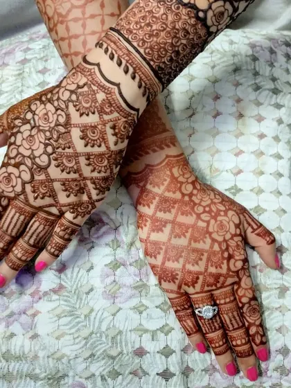 This design combines a floral grid pattern with a detailed wrist cuff. It's a great example of how different henna elements can be combined for a unique look.