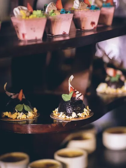 A display of various miniature desserts, including chocolate cakes and fruit mousses.