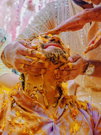 A close-up of the groom getting completely covered in Haldi by his loved ones. It's a messy, happy, and unforgettable moment.