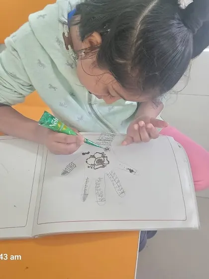 Another student carefully applies mehndi, enjoying a fun and traditional art form during the camp.