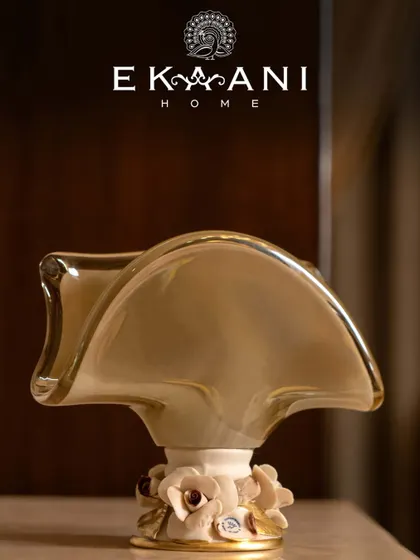 A sculptural vase from Murano, this piece blends a fluid, abstract form with delicate floral accents at the base. Handcrafted in glass and ceramic, it is a quiet showstopper, graceful and one of a kind.