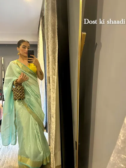 A mirror selfie in a simple mint green saree with a bright yellow blouse. This is a great look for a friend's daytime wedding event.