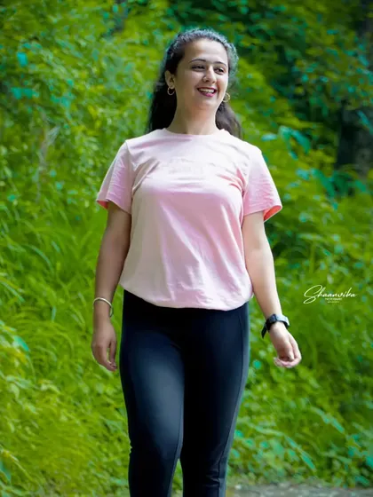 A happy, candid shot of the bride-to-be walking and smiling. The natural light and green background make this a fresh and lively portrait.