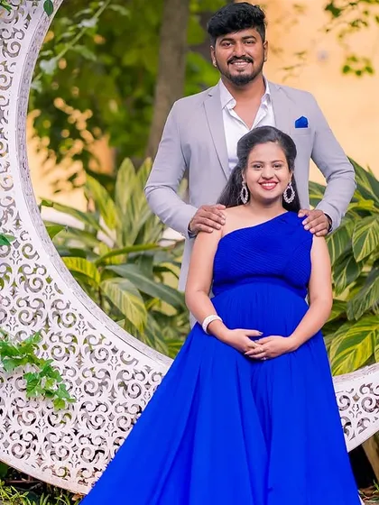 The crescent moon prop is a favorite for creating dreamy maternity photos. Here, the expecting couple poses together, with the mom-to-be seated on the moon, surrounded by a beautiful garden.