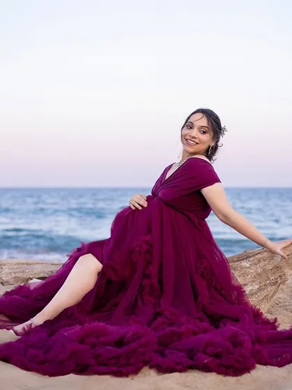 A relaxed and happy portrait of the mom-to-be sitting on a piece of driftwood, enjoying the beauty of the beach.