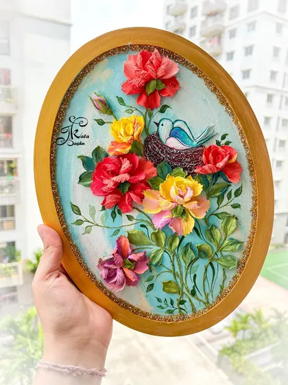 A sweet scene of a little bird in its nest, surrounded by a garden of red and yellow roses. This oval panel combines painting for the bird with 3D sculpture for the flowers and nest, creating a lovely story.