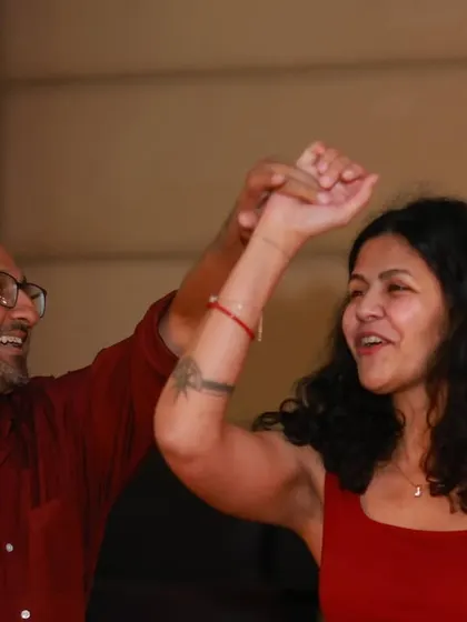 A couple mid-turn, smiling and having a great time. The woman is wearing red, adding a pop of color to the vibrant scene.