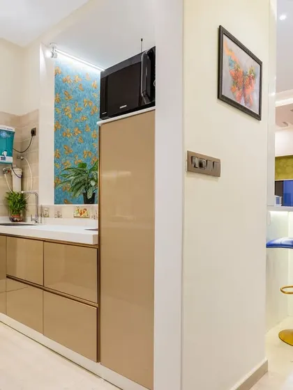 A view from the kitchen into the living area of the same Mumbai home, showing the open layout and the stylish breakfast bar with blue stools.