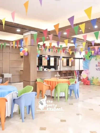 The entire venue for the art-themed party was filled with color, from the rainbow bunting flags hanging from the ceiling to the multi-colored chairs and tablecloths, creating a cheerful and inspiring atmosphere.