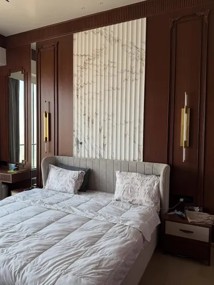 The final look of the luxury master bedroom, featuring rich brown wood paneling, a fluted marble-finish headboard wall, and elegant bedside sconces.