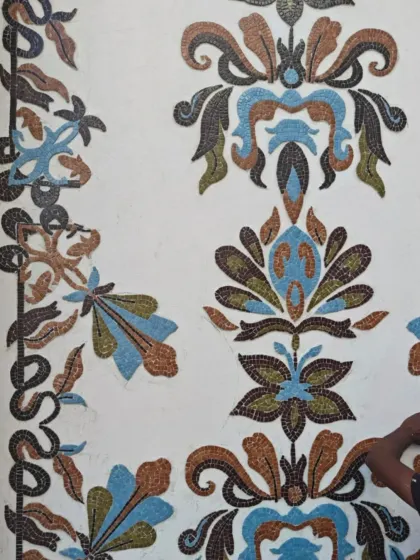 The mosaic panels being installed on the wall, revealing the intricate floral and damask-inspired patterns.