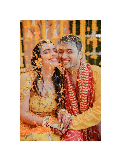Drenched in love, laughter, and flower petals. This candid shot from a Haldi ceremony captures the couple in a moment of pure, uninhibited joy.