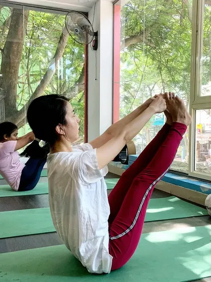 A student holds Navasana (Boat Pose), a core-strengthening posture that builds abdominal strength and balance.