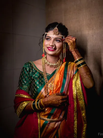 A Maharashtrian bride adjusting her Mundavalya, a key piece of bridal jewelry. This portrait captures the final touches before the ceremony begins.