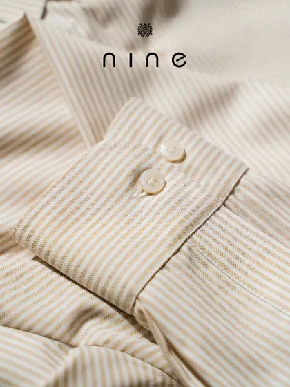 A close-up of the cuff on our beige and white striped summer shirt. The precise stitching and quality buttons are hallmarks of our craftsmanship.