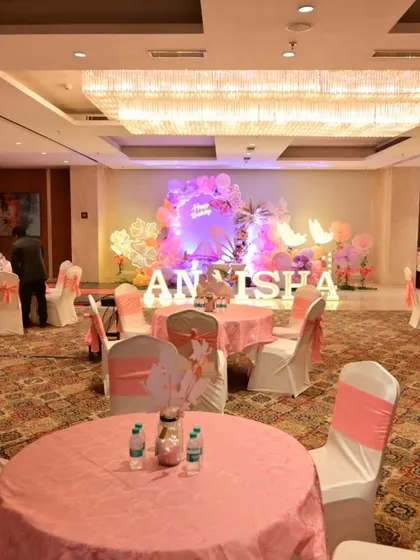A wide view of the banquet hall for Anaisha's birthday, showing the main stage decor and the coordinated pink table settings for guests.