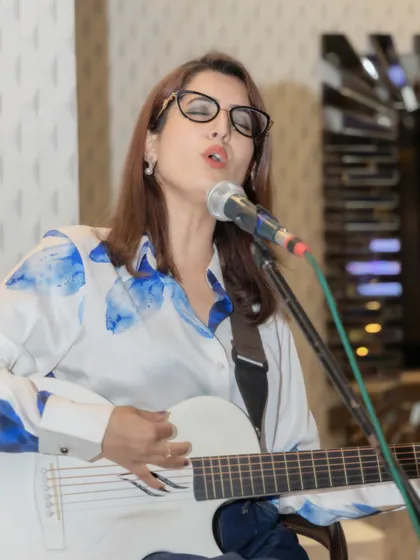 I'm mid-song with my eyes closed and my white guitar across me, photographed during the private celebration.