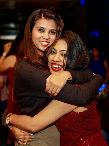 Two friends hugging and smiling, sharing a happy moment during our Christmas party.