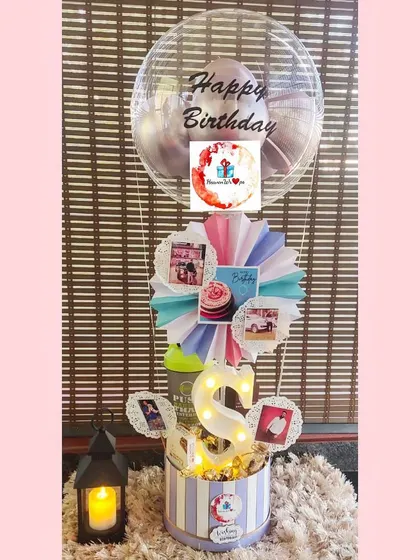 A personalized balloon hamper for a birthday celebration. This gift features a light-up initial 'S', a custom balloon, and photos arranged in a decorative box.