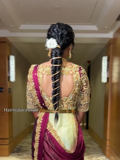 A modern half-saree drape for an engagement. The dupatta is styled with a unique twist, and the hair is in a contemporary wrapped braid, creating a chic and elegant look.