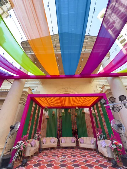 The full view of the vibrant Mehendi stage, set under a canopy of multi-colored drapes, ready for a day of fun and festivities.