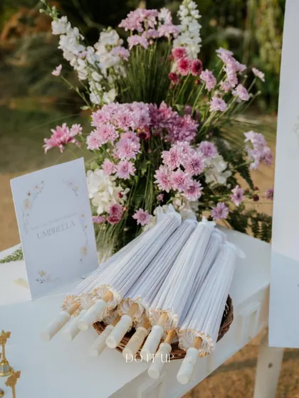 Providing elegant paper umbrellas for guests at a sunny, outdoor wedding is a thoughtful touch that ensures everyone's comfort while also adding to the visual aesthetic.