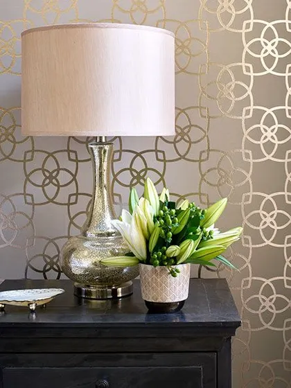 This wallpaper features a delicate, interlocking geometric pattern in gold on a neutral background. It adds a touch of elegance and shine to the room.