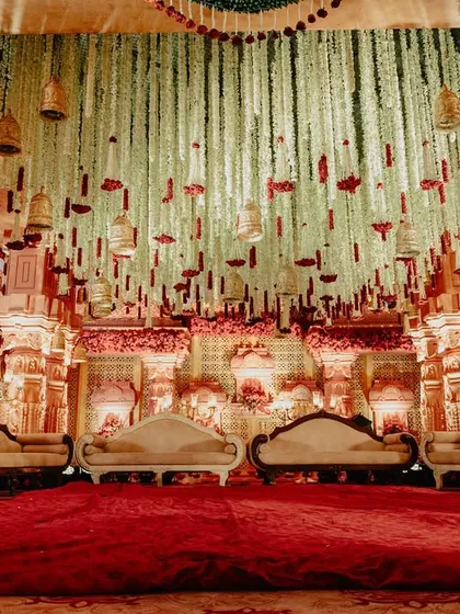 Inside the mandap, looking up at the ceiling adorned with thousands of hanging jasmine and tuberose strings (rajnigandha) and traditional temple bells.