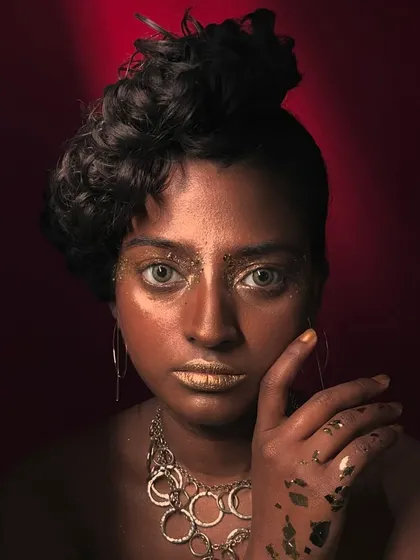 A close-up portrait from the gold foil editorial shoot, focusing on the intense gaze and the texture of the makeup.
