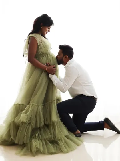 A classic pose where the partner kneels to kiss the baby bump, expressing love and excitement for the new arrival.
