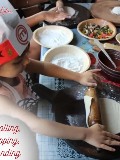 Rolling, topping, and bonding. A young participant carefully rolls out her dough with all the toppings ready to go. It's a great bonding activity for families.