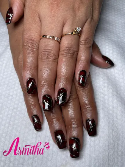 A full view of the hands, showing how the cohesive red and gold marble design looks across all ten nails, creating a powerful and elegant statement.
