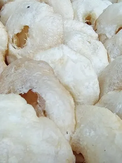 A pile of crispy, white Sandige. These sun-dried rice flour fryums are a traditional accompaniment, adding a satisfying crunch to the banana leaf meal.