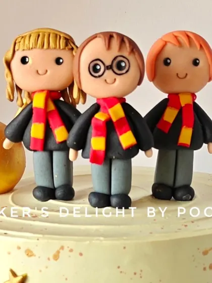 A close-up of the handcrafted fondant figurines of Harry, Hermione, and Ron. Creating these characters with their Gryffindor scarves was a magical process.