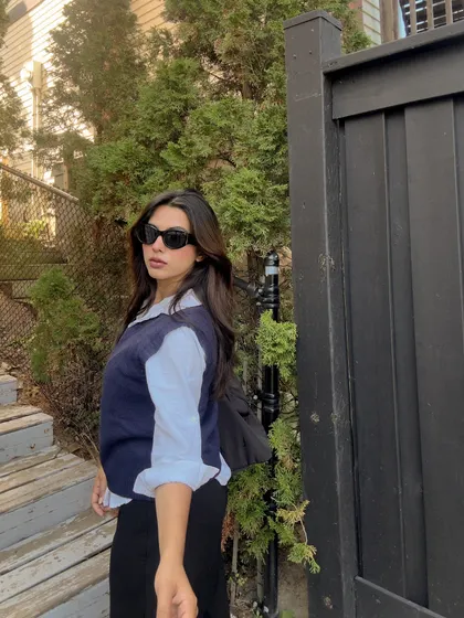 A side profile of the chic and academic-inspired sweater vest look.